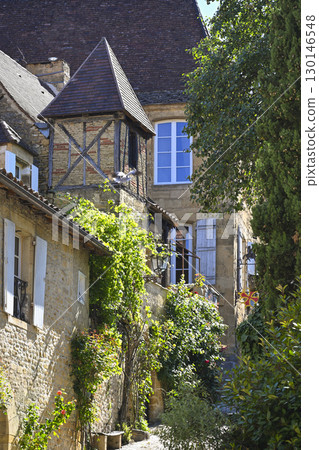 Charming street in Sarlat, Dordogne, featuring traditional architecture and lush greenery along Rue 130146548
