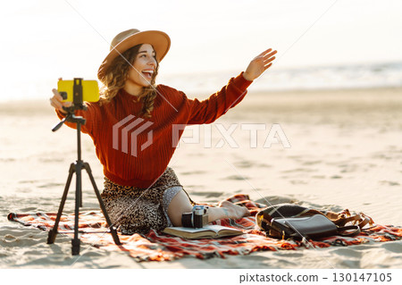 Happy woman using smartphone with stabilizer, live video in on sea beach. Live session blogging. 130147105