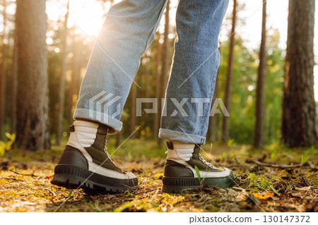 Feet of an adult wearing boots to travel walking in the forest. Feet walking in outdoor nature 130147372