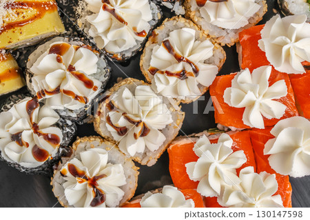 Assorted sushi rolls topped with cream cheese and sauce 130147598