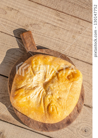 Whole smoked cheese on rustic wooden board. Top view. Copy space 130147752