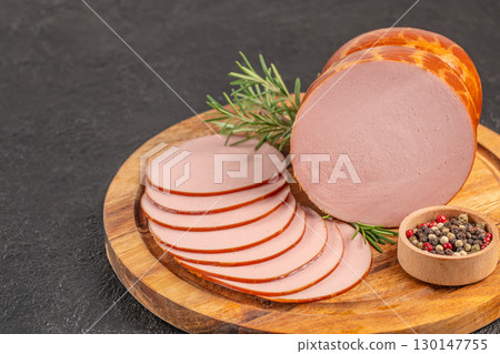 Sliced smoked sausage with pepper and rosemary on wooden board. top view. copy space 130147755