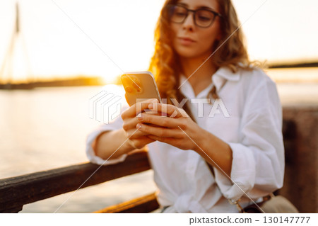 Phone in woman's hands. Communication with friends. Travel, tourism, technology, blogging concept. Phone in woman's hands. Communication with friends. Travel, tourism, technology, blogging concept. 130147777