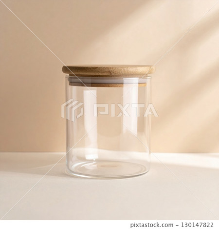 Minimalist Clear Glass Jar with Wooden Lid on Beige Tabletop Under Soft Lighting 130147822