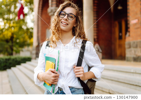 Student woman outdoors with bag and books near University. Education, friendship and people concept 130147900