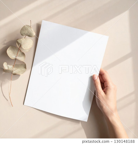 Hand Holding White Paper Sheet with Eucalyptus Branch on Beige Surface Hand Holding White Paper Sheet with Eucalyptus Branch on Beige Surface 130148188