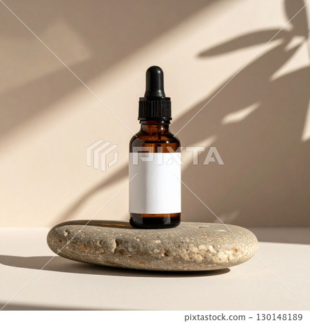 Amber Dropper Bottle with Blank Label on Gray Stone with Leaf Shadows Amber Dropper Bottle with Blank Label on Gray Stone with Leaf Shadows 130148189