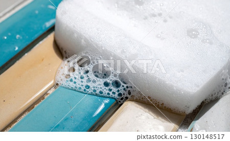 Close Up of White Foam Sponge on Colorful Rectangular Tiles With Bubble Texture in Bright Sunlight Close Up of White Foam Sponge on Colorful Rectangular Tiles With Bubble Texture in Bright Sunlight 130148517