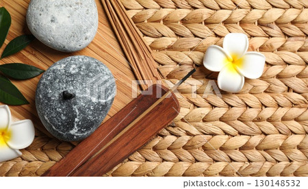 Spa Still Life with Stones Frangipani Incense Sticks and Green Leaves on Woven Mat 130148532