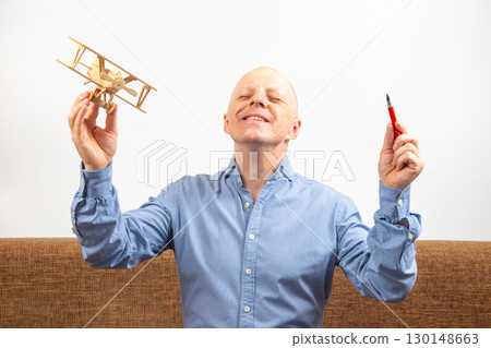Dream of flight. inventor concept. man with a bald head and a blue shirt joyfully raises Dream of flight. inventor concept. man with a bald head and a blue shirt joyfully raises 130148663