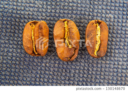Close-up of roasted coffee beans scattered on a dark textured background 130148670