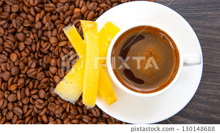 Rich espresso in a white cup paired with cheese sticks, nestled among coffee beans  130148688
