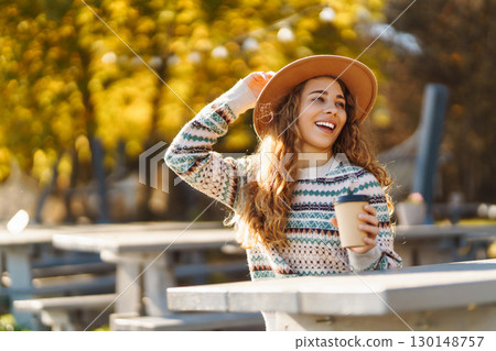 Fall concept woman drinking coffee on bench against backdrop of lake. Enjoying, solitude with nature 130148757