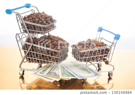 small shopping cart filled with roasted coffee beans sits on a golden surface 130148984