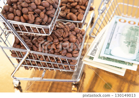 A small cart packed with coffee beans rests on a gold table with $100 bills A small cart packed with coffee beans rests on a gold table with $100 bills 130149013