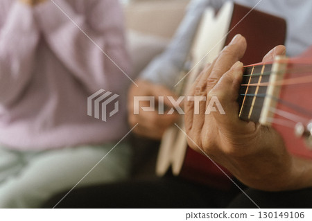 Happy Senior Couple Enjoying Retirement Together Playing Musical Instruments at Home in Bright Sunshine 130149106