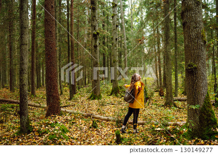 Female tourist with backpack in forest walks, enjoys nature of forest. Concept of nature, relaxation Female tourist with backpack in forest walks, enjoys nature of forest. Concept of nature, relaxation 130149277