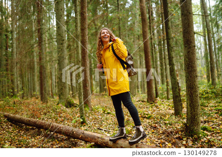 Female tourist with backpack in forest walks, enjoys nature of forest. Concept of nature, relaxation Female tourist with backpack in forest walks, enjoys nature of forest. Concept of nature, relaxation 130149278