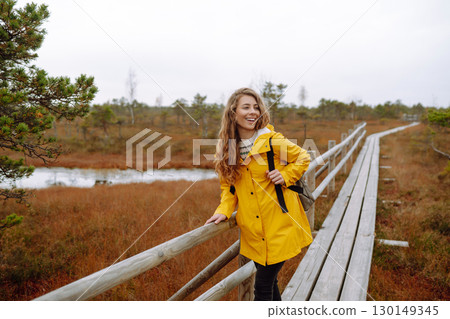 Portrait of happy woman walking along path among marsh nature. Concept of travel. Active lifestyle. 130149345
