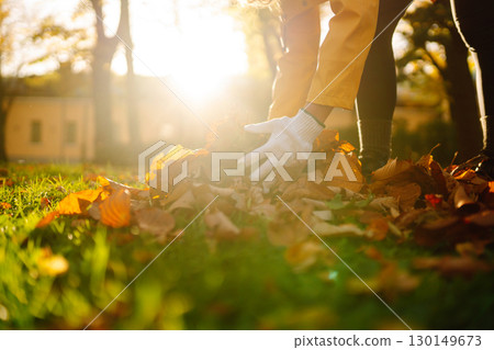 Woman cleans autumn park from yellow leaves. Volunteering, cleaning concept. Seasonal gardening. 130149673