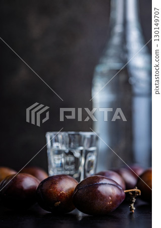 Plums and distilled alcohol on black table. Plum brandy shot. Plums and distilled alcohol on black table. Plum brandy shot. 130149707