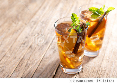 Refreshing peach iced tea in glass with ice cubes and cinnamon 130151323