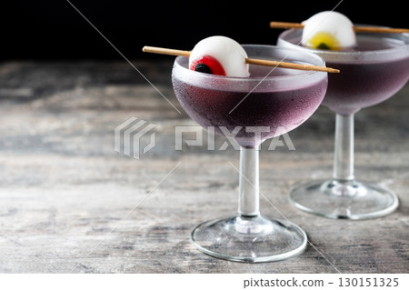 Purple Halloween cocktail garnished with candy eye Purple Halloween cocktail garnished with candy eye 130151325