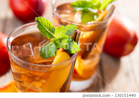 Refreshing peach iced tea in glass with ice cubes and cinnamon 130151440
