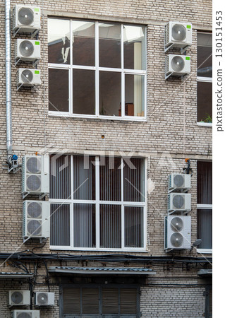 Facade of building with many air conditioners on windows in southern hot country. Escape from heat Facade of building with many air conditioners on windows in southern hot country. Escape from heat 130151453