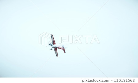 Aerobatic airplane performing stunt with smoke trail in the sky Aerobatic airplane performing stunt with smoke trail in the sky 130151568