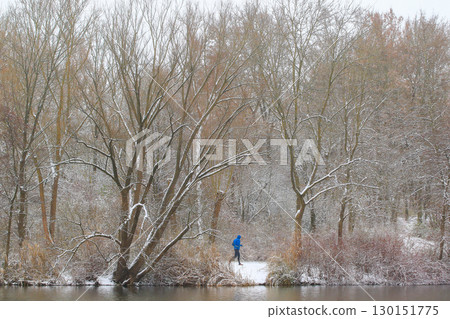People Walking Through Snowy Forest by Lake 130151775