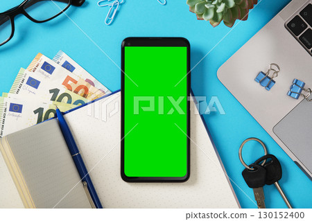 Smartphone mockup with green screen on desk next to laptop, notebook, euro banknotes, and stationery. Demonstration for your mobile app. Smartphone mockup with green screen on desk next to laptop, notebook, euro banknotes, and stationery. Demonstration for your mobile app. 130152400