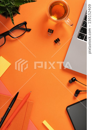 Blank notebook with office stationery, laptop, and cup of tea on orange desk. Workspace for study, planning. Copyspace. Blank notebook with office stationery, laptop, and cup of tea on orange desk. Workspace for study, planning. Copyspace. 130152409