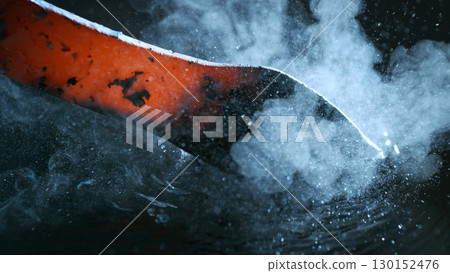 Blacksmith puts the red-hot forged metal part into cold water , close-up 130152476