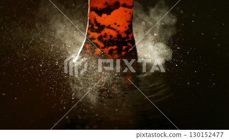 Blacksmith puts the red-hot forged metal part into cold water , close-up 130152477