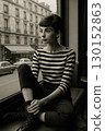 A black and white portrait of a woman looking out a cafe window 130152863