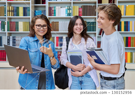 Two teenage students meeting talking with female teacher in library 130152956
