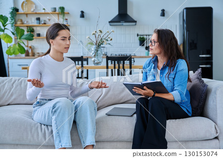 Female social worker working at home with teenage girl Female social worker working at home with teenage girl 130153074