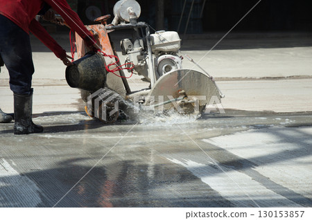 Workers are using a concrete road cutter. 130153857