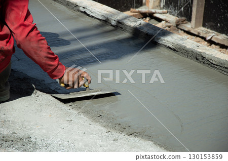 Workers are leveling the floor after pouring concrete. 130153859
