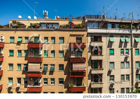 Facade of residential apartment buildings with balconies, plants and antennas under clear blue sky in Rome, Italy Facade of residential apartment buildings with balconies, plants and antennas under clear blue sky in Rome, Italy 130153970