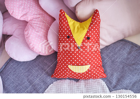 Colorful polka dot fox pillow among soft pink and gray textured cushions Colorful polka dot fox pillow among soft pink and gray textured cushions 130154556