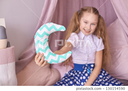 Young caucasian girl holding decorative crescent moon pillow in cozy room Young caucasian girl holding decorative crescent moon pillow in cozy room 130154590