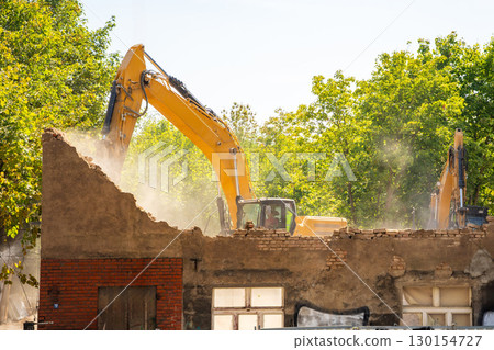 Excavator demolishing an old building on a city street. Concept of urban redevelopment, structural dismantling and transformation of city architecture Excavator demolishing an old building on a city street. Concept of urban redevelopment, structural dismantling and transformation of city architecture 130154727