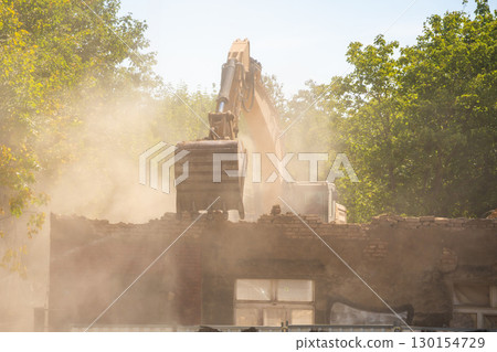 Excavator demolishing an old building on a city street. Concept of urban redevelopment, structural dismantling and transformation of city architecture 130154729