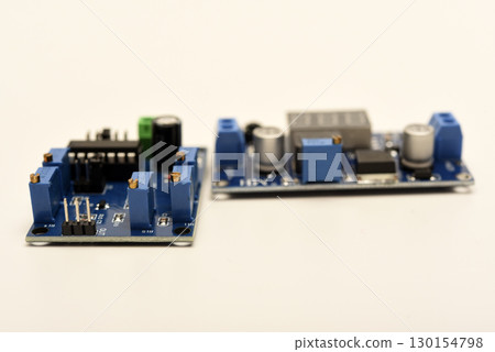 Two electronic devices on a blue printed circuit board. A small electronic device. Two electronic devices on a blue printed circuit board. A small electronic device. 130154798