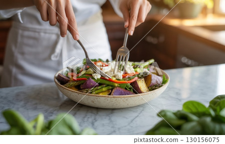 Woman hands mixing a vibrant healthy salad with fresh asparagus, sweet potato, and feta cheese 130156075