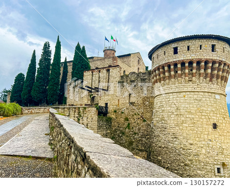 Ancient European castle with round tower and walkway along the top of the walls 130157272