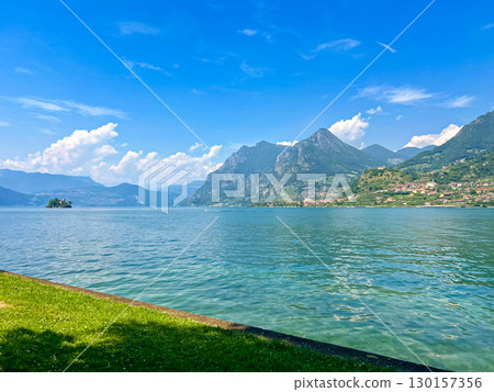 View of Iseo Lake Surrounded by Majestic Mountains and Clear Blue Skies, Italy 130157356