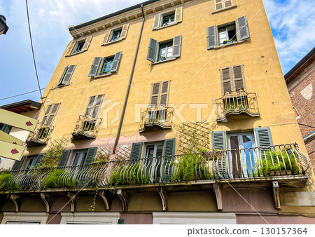Charming italian houses facade with balcony with lush greenery, Brescia 130157364